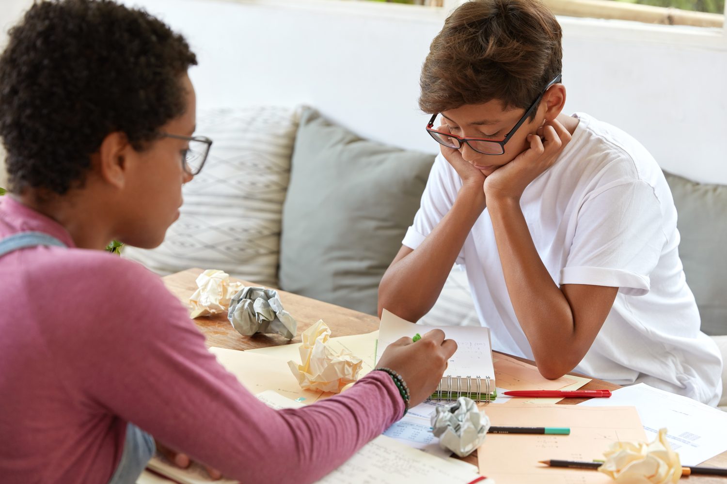 Two school-age students working through homework at a table
