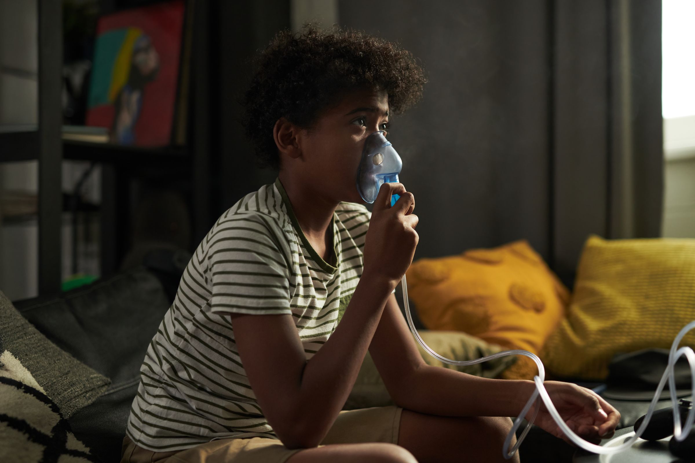 A young person at home breathing through a nebuliser mask