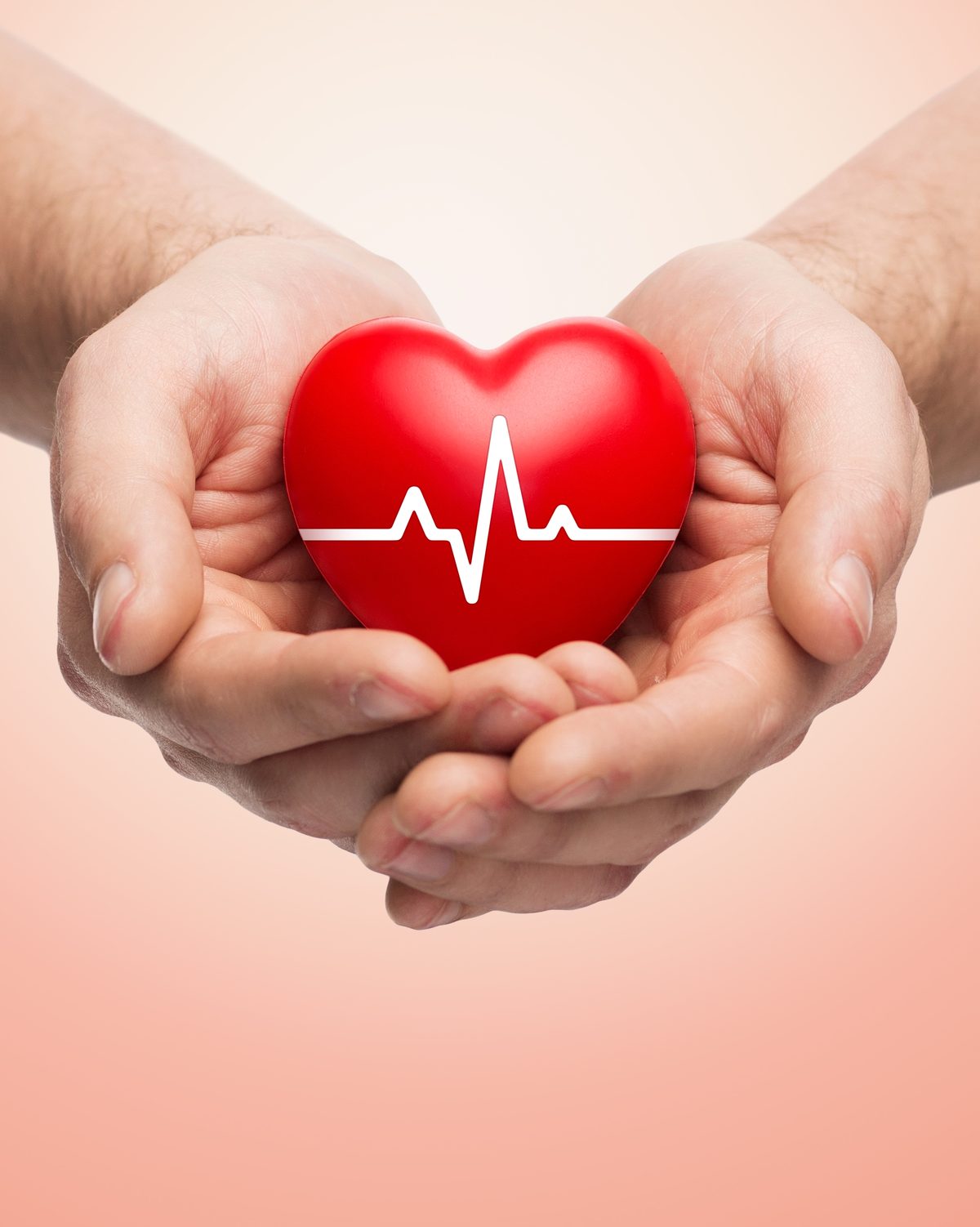 Hands cupping a red heart with a cardiogram line