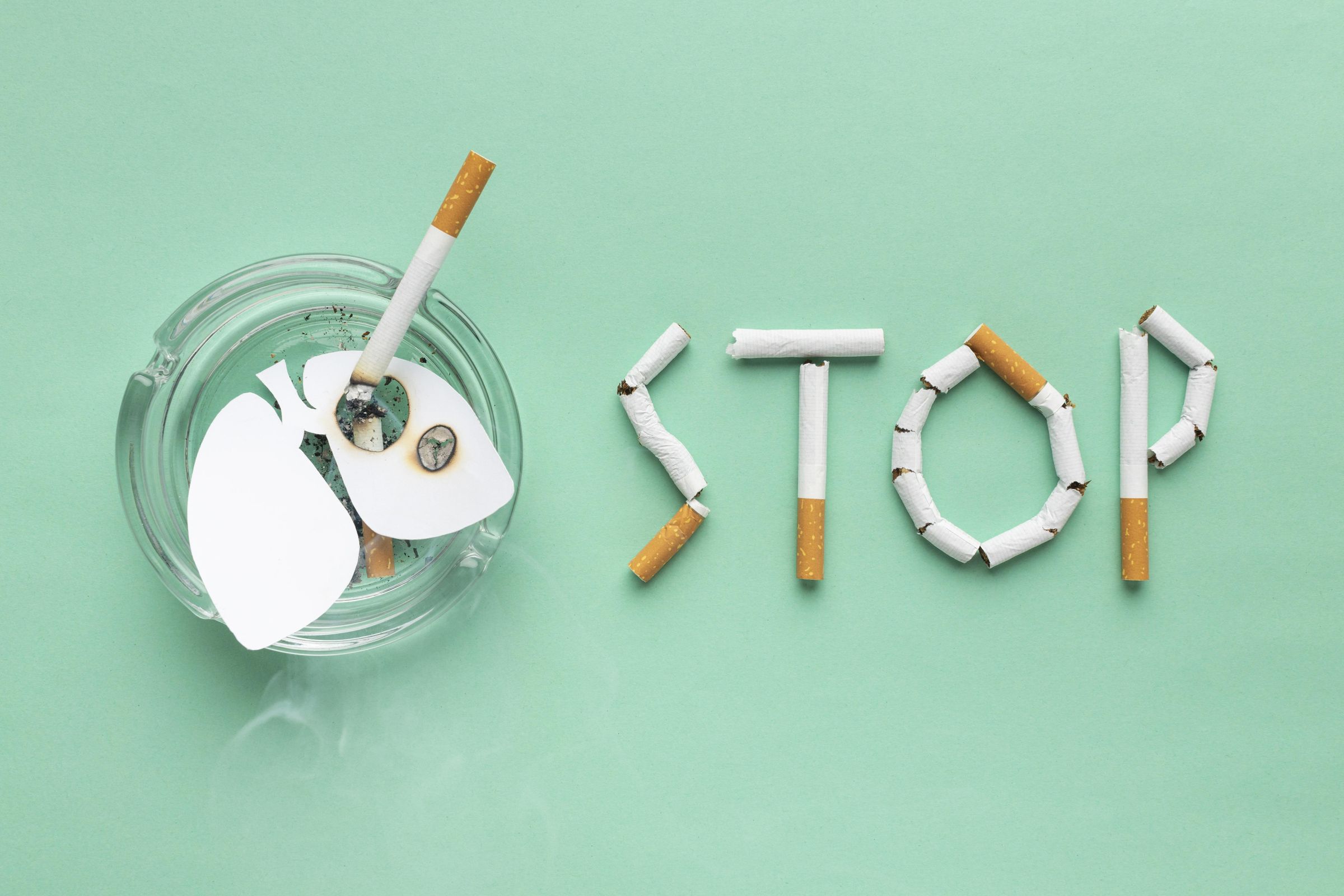 Broken cigarettes spelling the word stop beside an ashtray