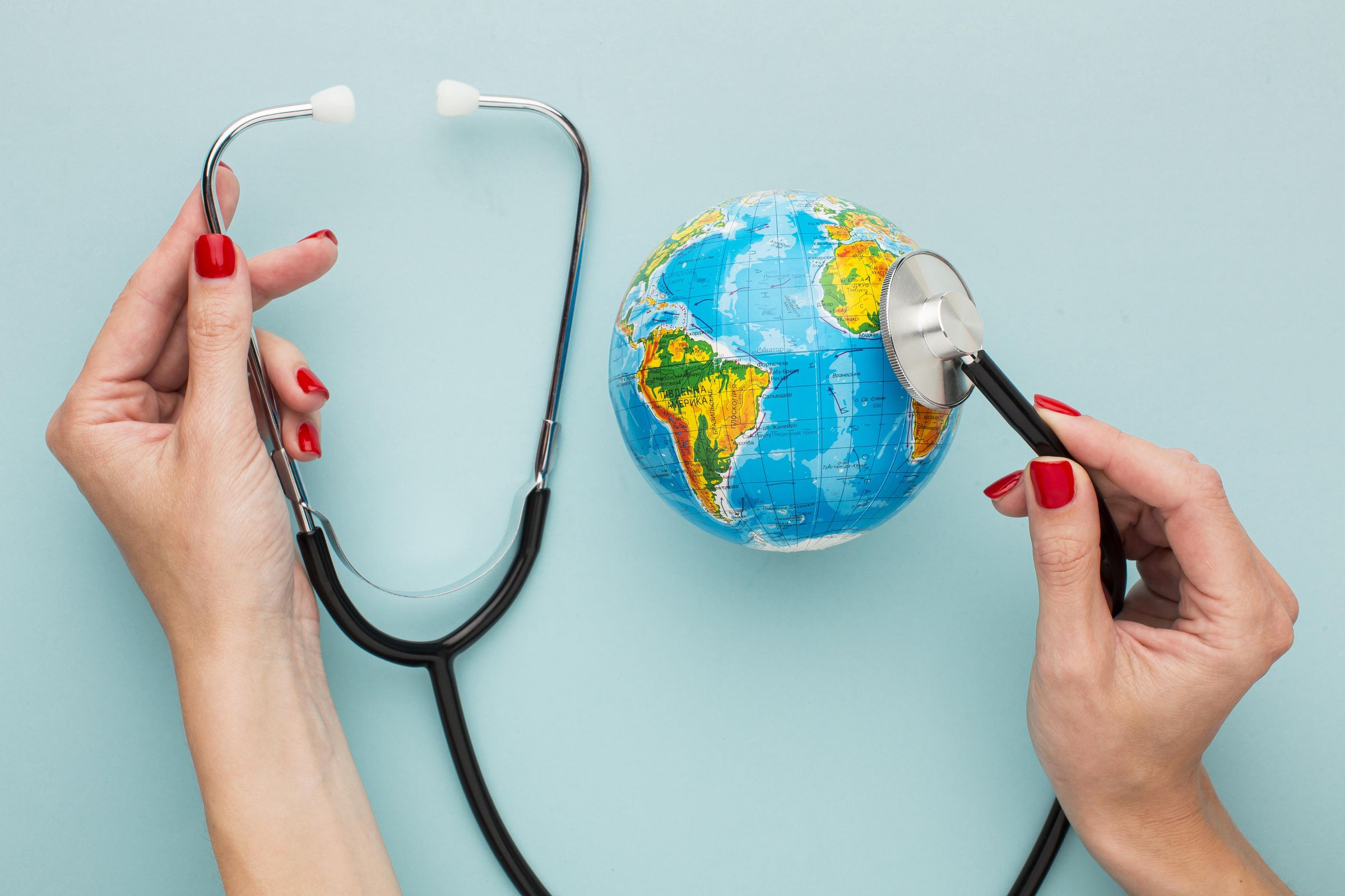 Hands holding a stethoscope to a small globe